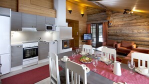 Et moderne køkken med rustfrit stål-hvidevarer, et spiseområde med et rødt borddække og en hyggelig opholdsstue med pejs.