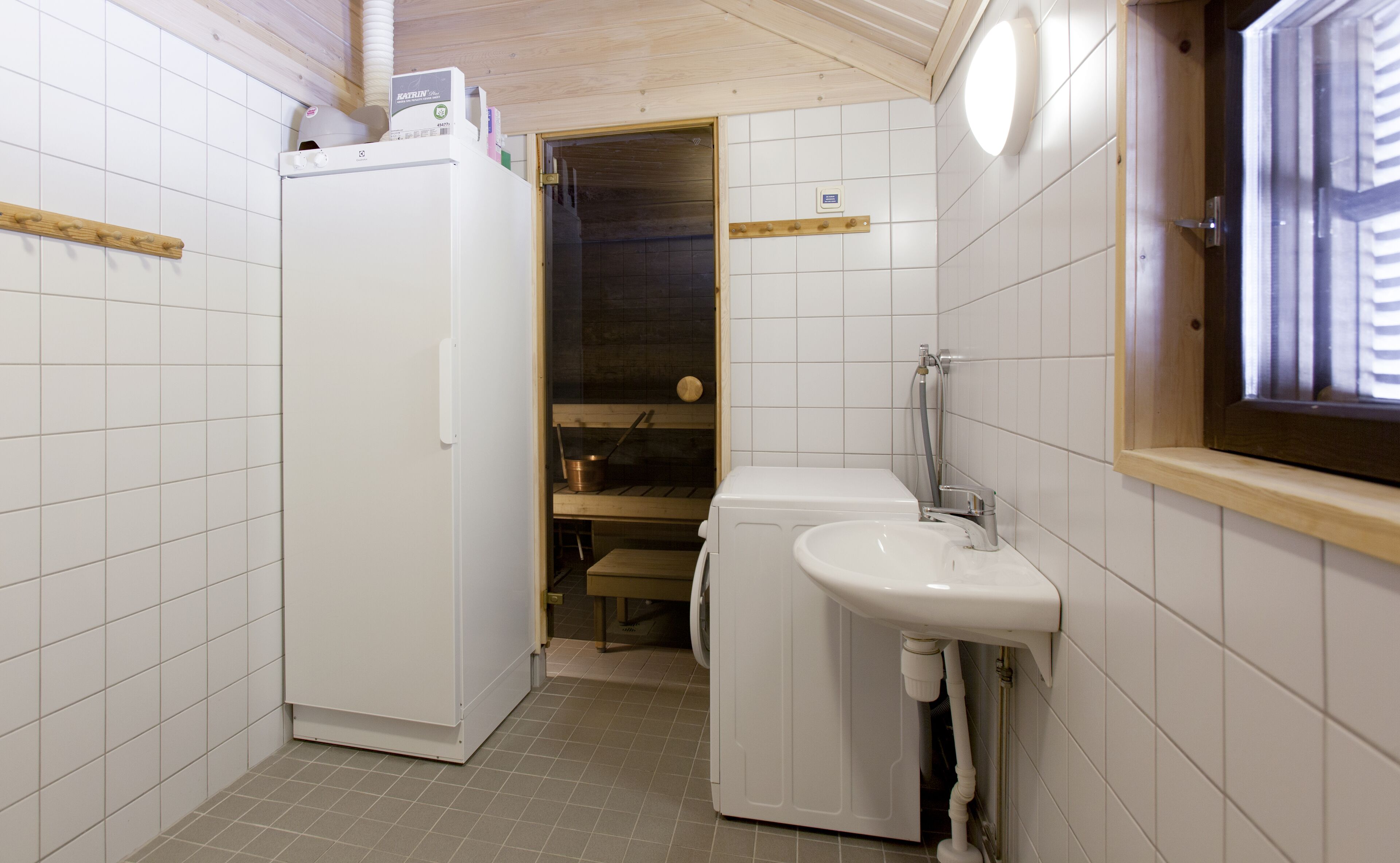A compact bathroom with a white sink, a toilet, and a built-in washing machine.