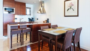 A modern kitchen with a central island, bar stools, and a dining table with chairs. - Holiday Club Naantali Apartments (Naantali)
