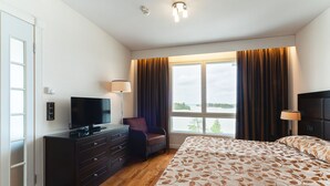 A hotel room with a bed, a TV, a dresser, a chair, and a window with curtains. - Holiday Club Naantali Apartments (Naantali)