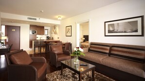 A modern living room with a sofa, chairs, a coffee table, and a rug. There is a kitchen area in the background with a dining table and chairs. - Holiday Club Naantali Apartments (Naantali)