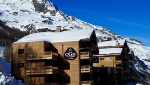 A wooden building with balconies and a sign for CGH Residence Hotelier Spa & Beauté. - CGH Le Lodge des Neiges (Tignes)