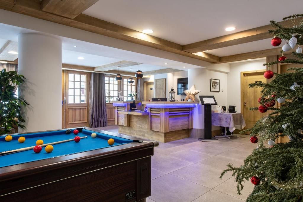 A pool table in a room with a reception desk, a Christmas tree, and a door leading to another area.
