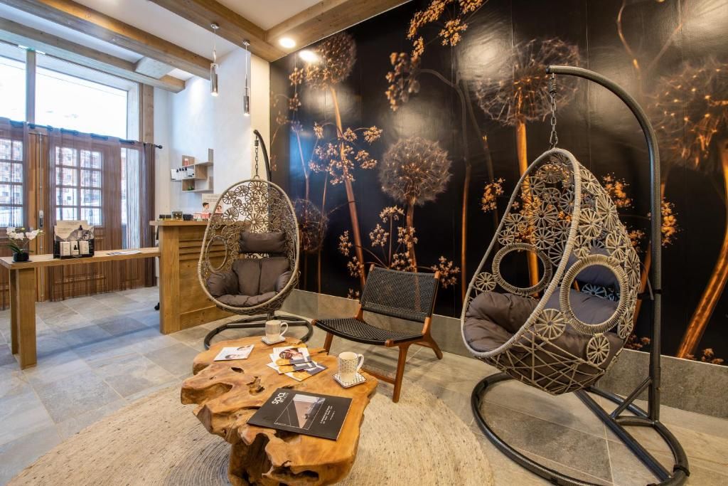 Um interior moderno com cadeiras penduradas, uma mesa de madeira e uma parede com estampas florais.