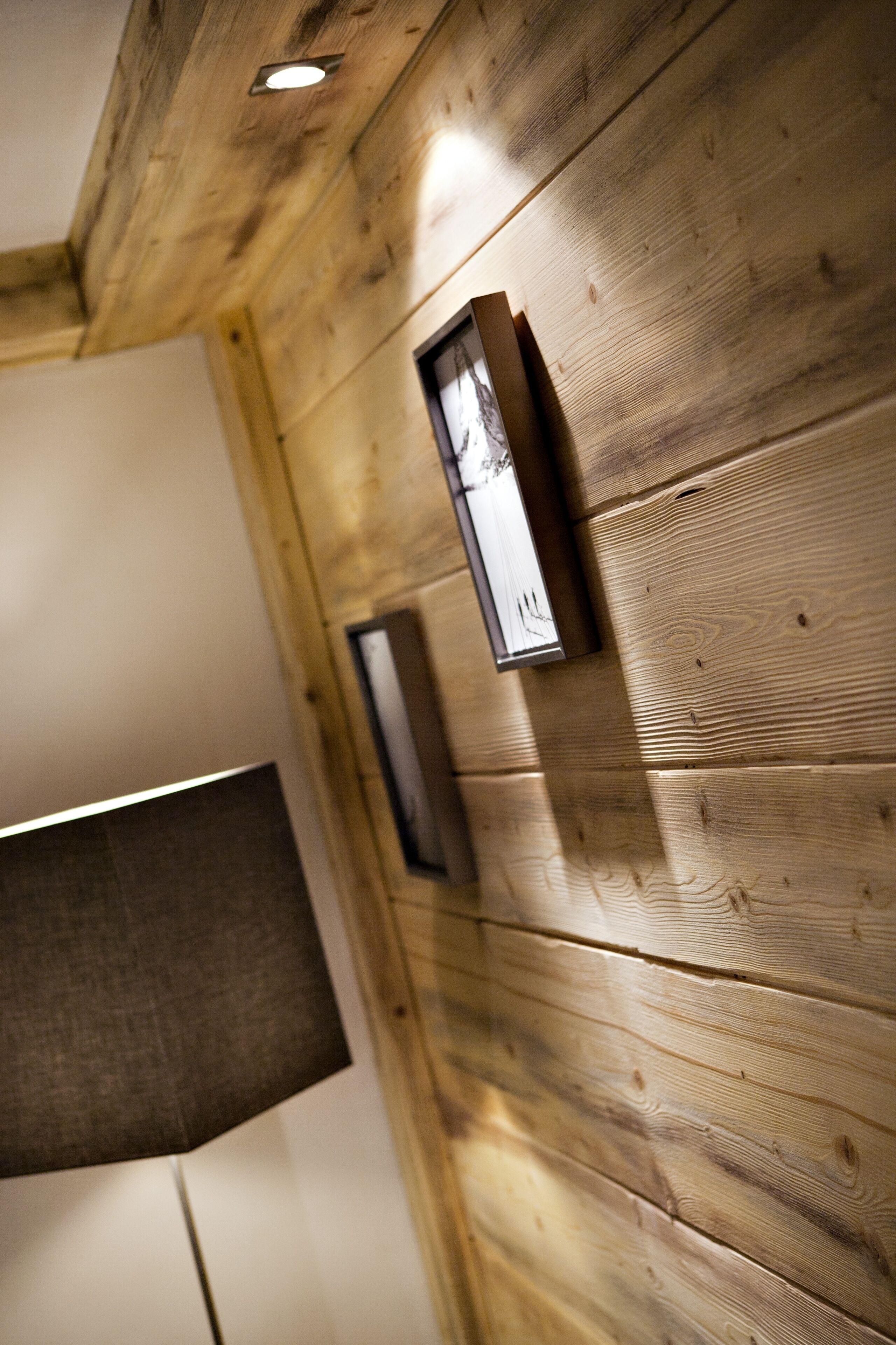 A wooden wall with a framed picture and a light fixture.