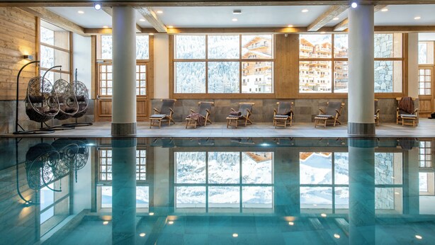 A pool area with clear views of a mountainous landscape through large windows. - CGH Le Lodge des Neiges (Tignes)