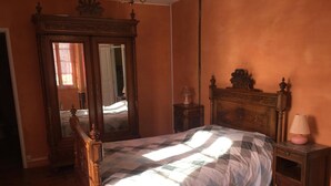 A bedroom with a wooden bed, a dresser, a mirror, and a nightstand.