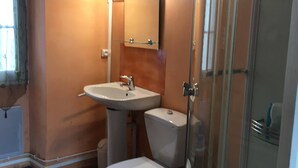 A bathroom with a sink, toilet, and glass shower enclosure.