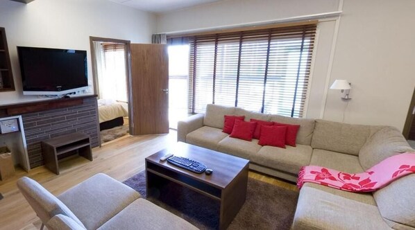 A living room with a TV, sofa, and coffee table. - Holiday Club Tahko Spa Apartments (Kuopio)