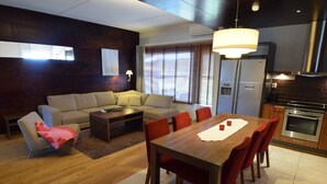Un salon moderne comprenant un canapé, une table basse et une table à manger avec des chaises. Il y a également un coin cuisine avec une cuisinière et un four.