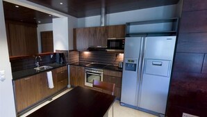 Une cuisine moderne avec des meubles en bois foncé, des appareils électroménagers en acier inoxydable et un plan de travail noir.