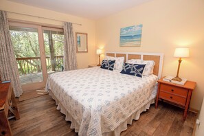 Relax in a serene bedroom with a large bed, nightstand, and dresser, plus a sliding door to an outdoor area.