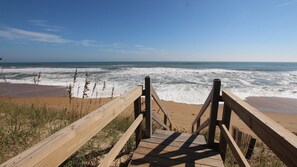 A wooden boardwalk leading to a beach with waves crashing onto the shore.