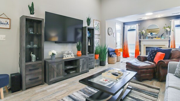 Een woonkamer met een flatscreen televisie, donker houten meubels, een open haard en uitzicht op de natuur.