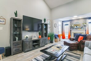 A living room with a flat-screen TV, dark wood furniture, a fireplace, and a view of the outdoors. - 3 Mi to Boardwalk: Bethany Beach House w/ Patio! (Millville)