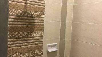 Una ducha con un revestimiento de pared estampado y otra pared con azulejos lisos.
