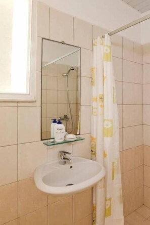 A bathroom with a sink, a mirror, and a shower. - Sveas Hotel (Rhodes)