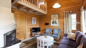 A cozy cabin interior with a fireplace, television, and seating area.