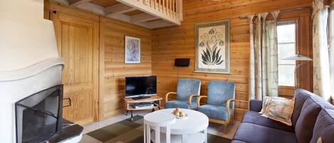 A cozy cabin interior with a fireplace, television, and seating area.