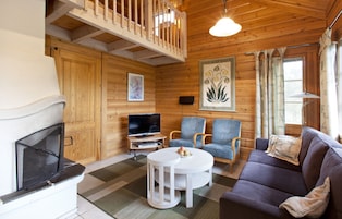 Interior acolhedor de uma cabana com lareira, televisão e área de estar.