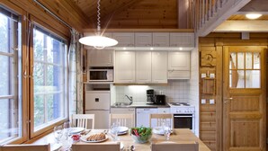 A wooden interior with a dining table set for four, white cabinets, a microwave, a coffee maker, and a wooden door.