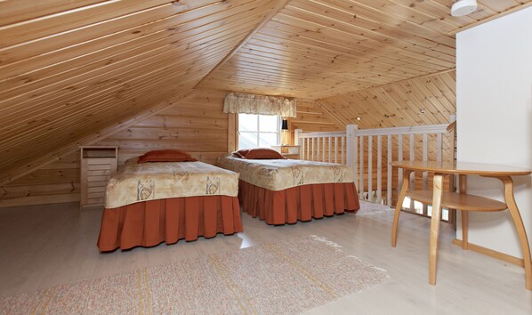 A cozy attic bedroom with two beds, a desk, and a window. - Holiday Club Ähtäri Cottages (Ahtari)