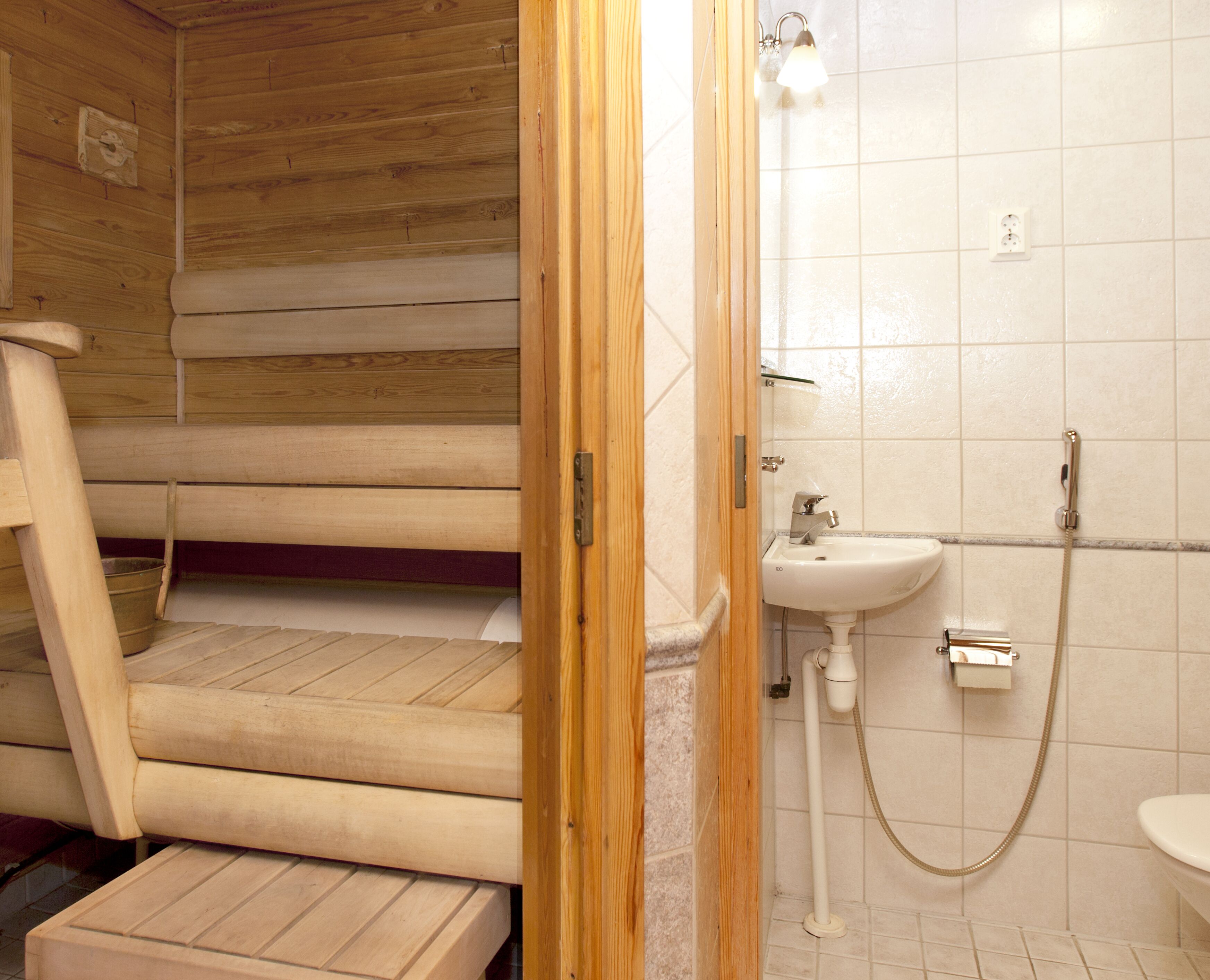 Un escalier en bois mène à une salle de bain équipée d’un lavabo et d’une douche.