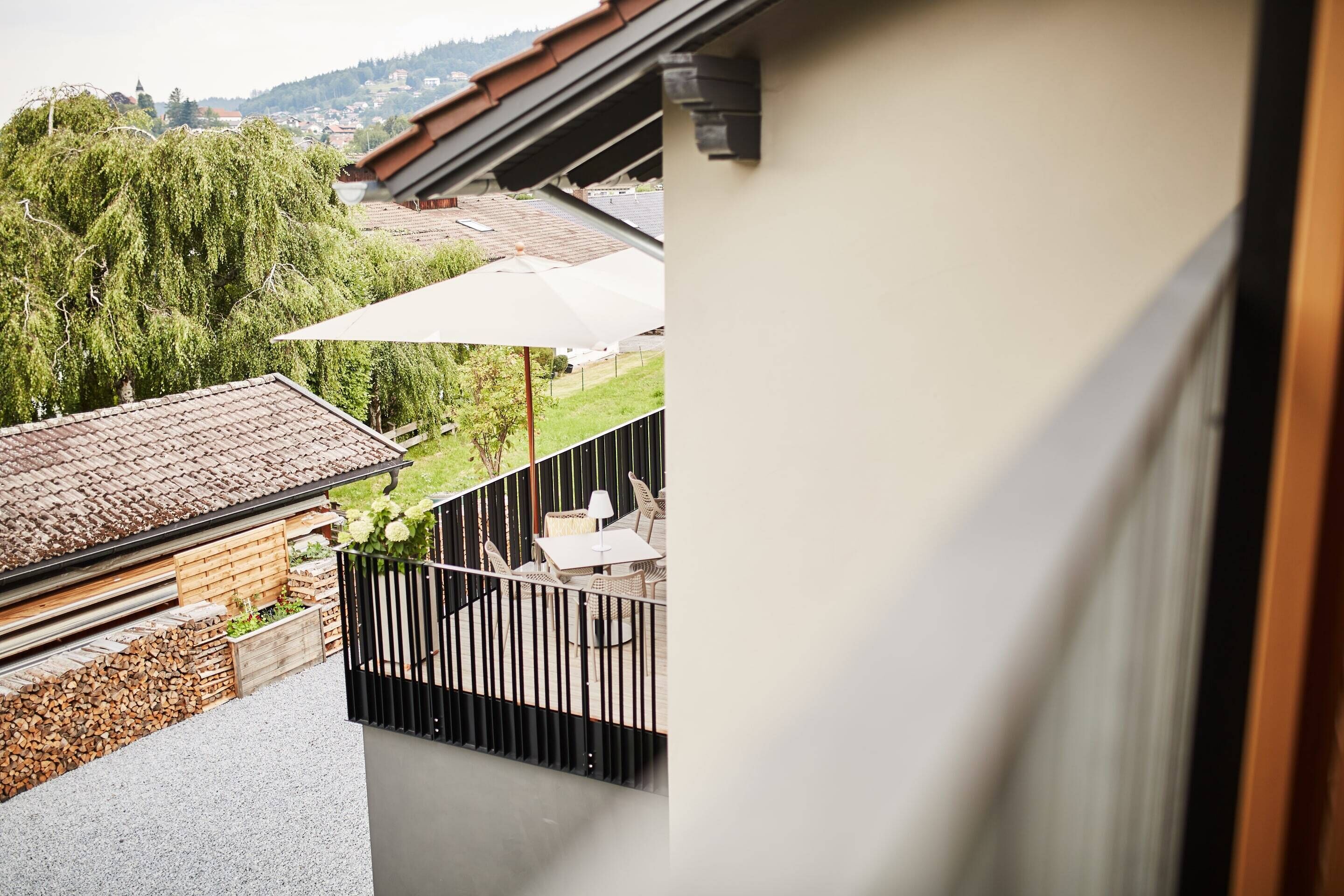 A balcony with a view of a garden and a neighboring building.