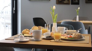 A breakfast table set with various food items and a vase of flowers. - Winterfeld Guest House Bodenmais (Bodenmais)