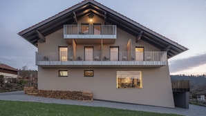 A modern two-story house with a balcony, a visible dining area, and a well-maintained lawn. - Winterfeld Guest House Bodenmais (Bodenmais)