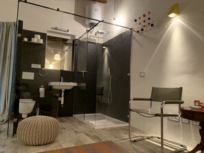 A modern bathroom with a glass-enclosed shower, a sink, and a chair. - Piccolo Appartemento Capoliveri (Capoliveri Isola'd Elba)