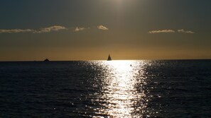 A sunset over a calm sea with a sailboat in the distance. - Piccolo Appartemento Capoliveri (Capoliveri Isola'd Elba)