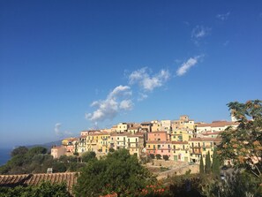 A hillside town with colorful buildings, a clear sky, and a view of the sea. - Piccolo Appartemento Capoliveri (Capoliveri Isola'd Elba)