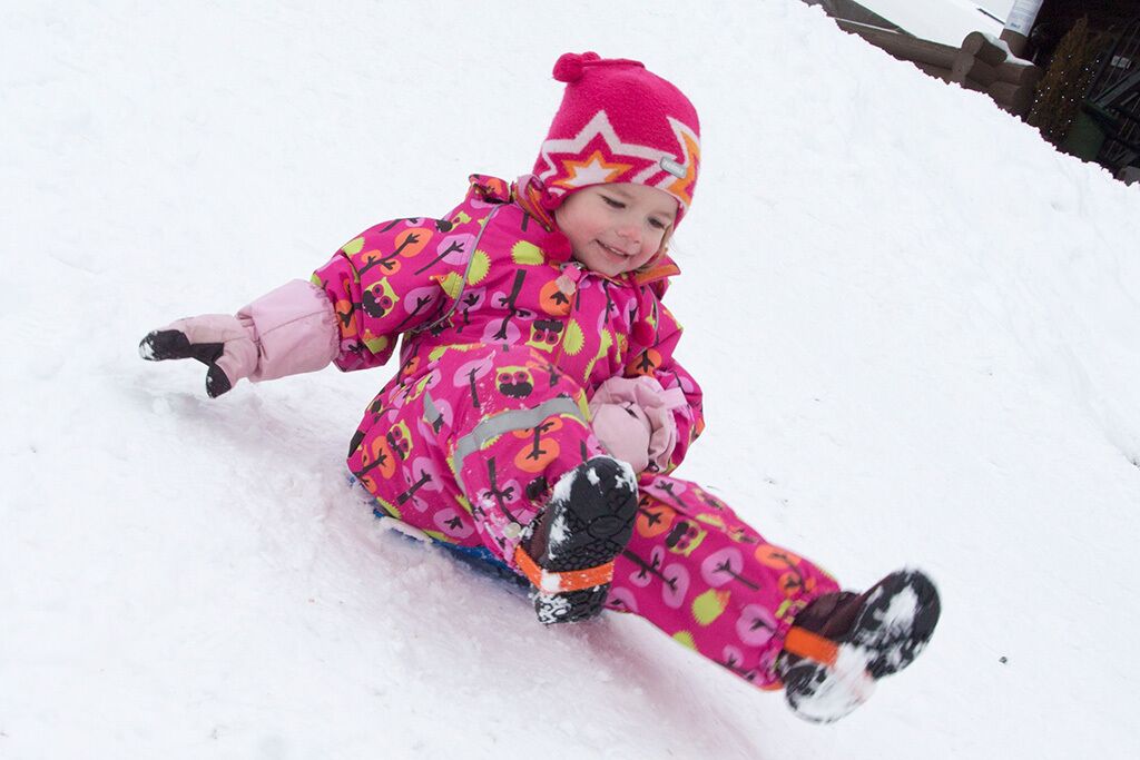 Un niño deslizándose en un trineo por una pendiente nevada.
