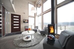 A modern living room with a fireplace, large windows, and a cozy seating area. - Holiday Club Himos Apartments (Jamsa)
