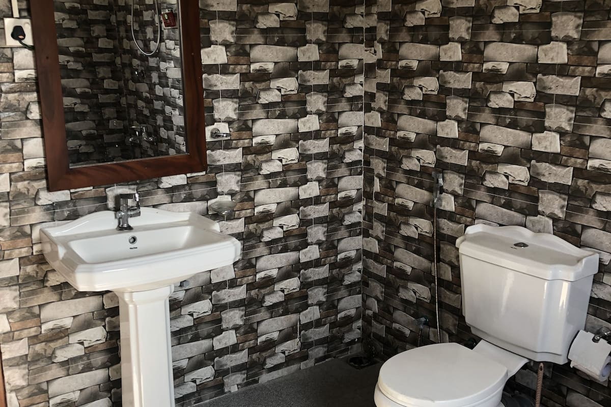 Une salle de bain avec des toilettes, un lavabo et un miroir. Le sol est recouvert de carreaux formant un motif décoratif.