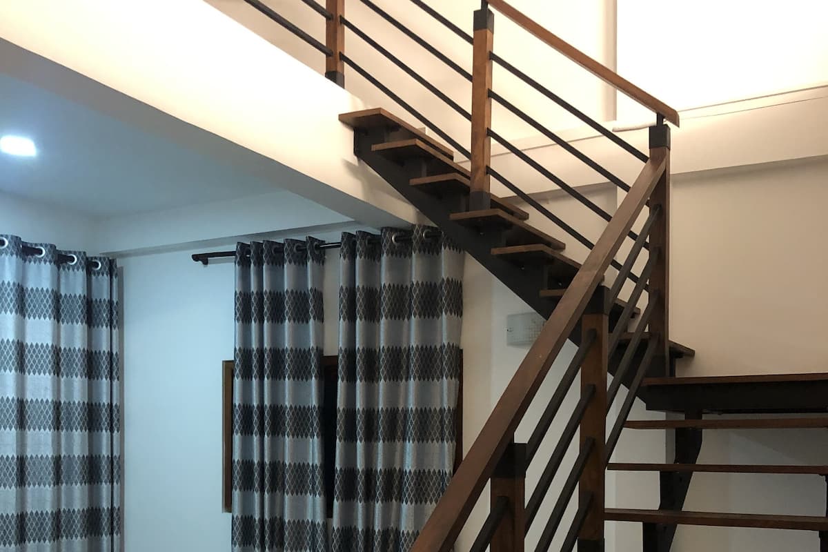 Un escalier avec une rampe en bois et un rideau à motifs à carreaux.