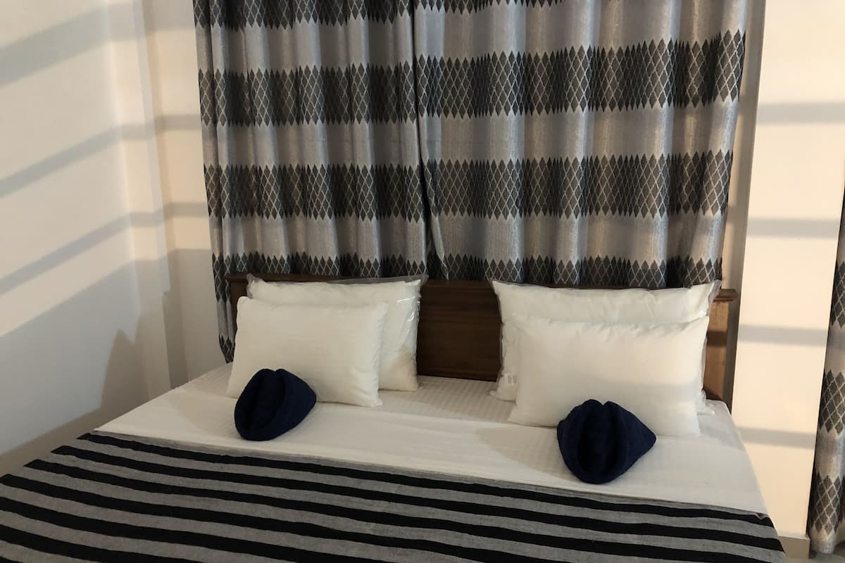 Un lit double avec des oreillers blancs et une couvre-lit à rayures.