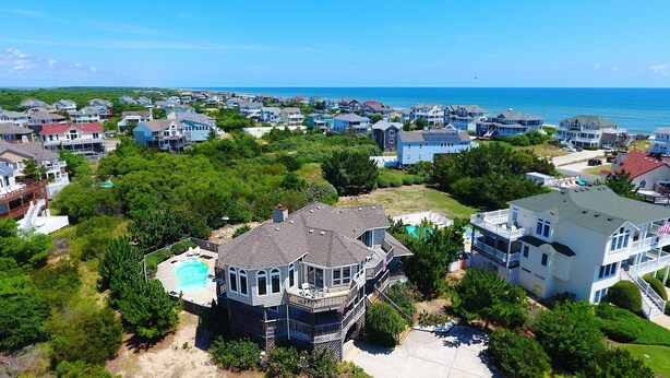 A coastal residential area with houses, a swimming pool, and a view of the ocean.