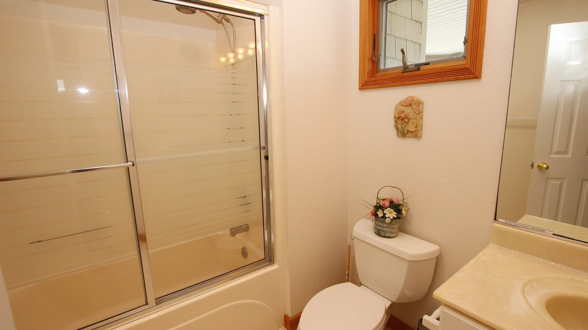 A bathroom with a glass shower enclosure, a toilet, and a sink.