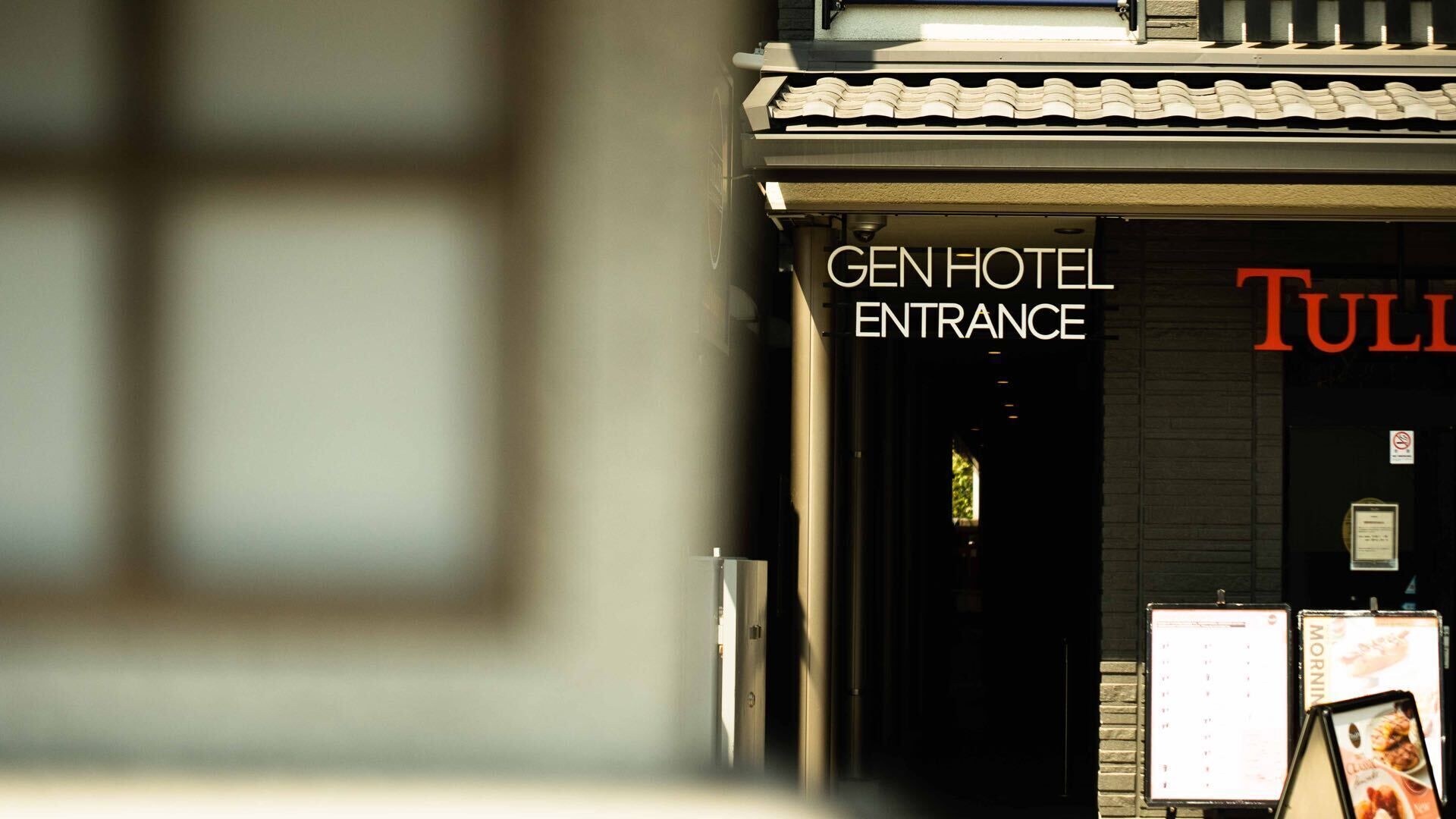 The entrance of the Gen Hotel with a sign above the door and a menu board to the right.