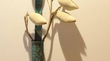 A vase with a rustic, weathered texture and a plant with elongated leaves.