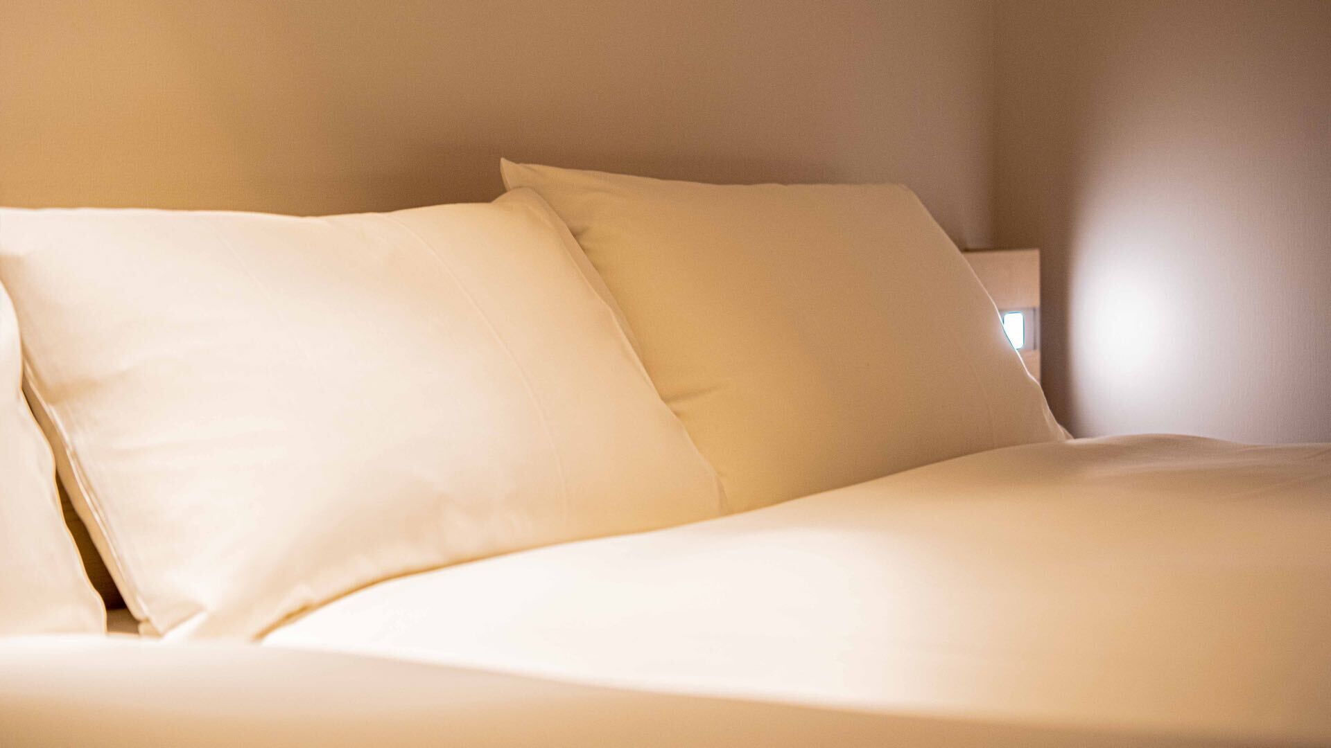 A bed with white bedding and pillows.