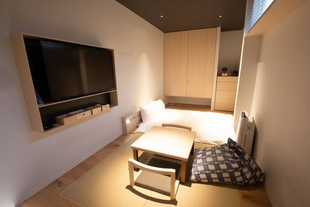 A compact bedroom with a bed, bedside table, and a mounted TV.