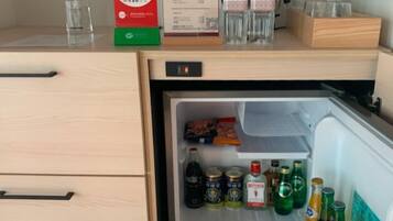 A hotel minibar with a refrigerator containing various beverages and snacks.