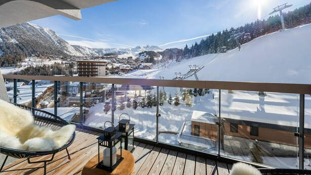 A balcony with a view of a snowy mountain landscape, including a ski lift and buildings. - Winter Courchevel -- Phoenix 603 (Courchevel)