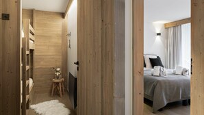 A wooden interior with a bed, a small stool, and a white furry rug. - Winter Courchevel -- Phoenix 603 (Courchevel)