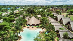A resort with thatched-roof cottages, a central pool, and lush greenery. - Sandy's Creations Resort (Lusaka)