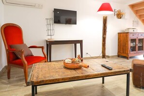 A living room with a wooden coffee table, a red chair, a television, and a lamp.
