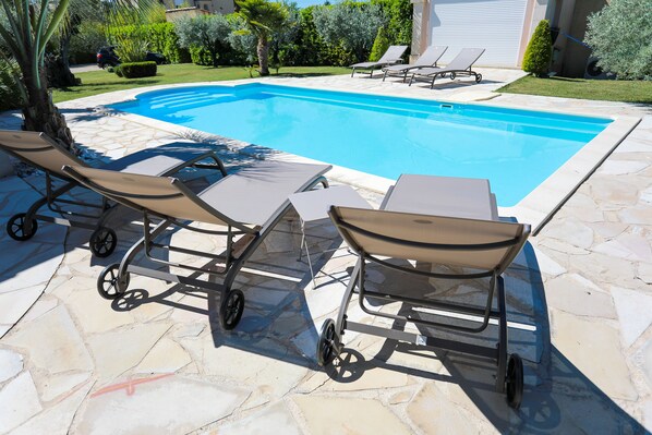 A swimming pool with lounge chairs and a cart.